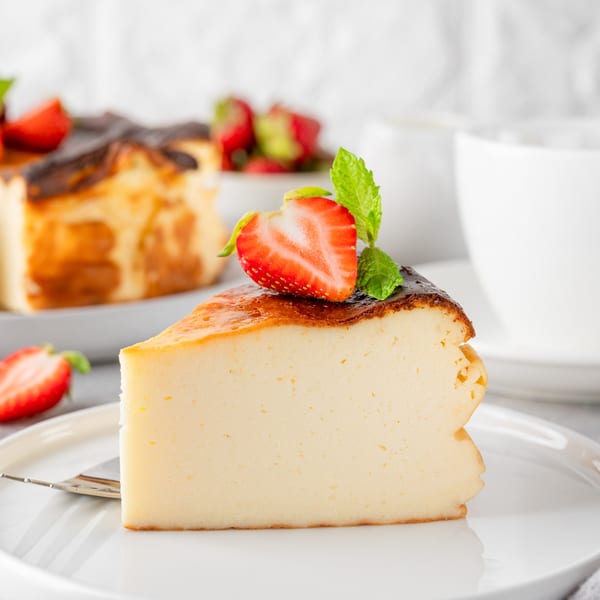 Slice of Italian cheesecake with a burnt top, garnished with a strawberry and mint.